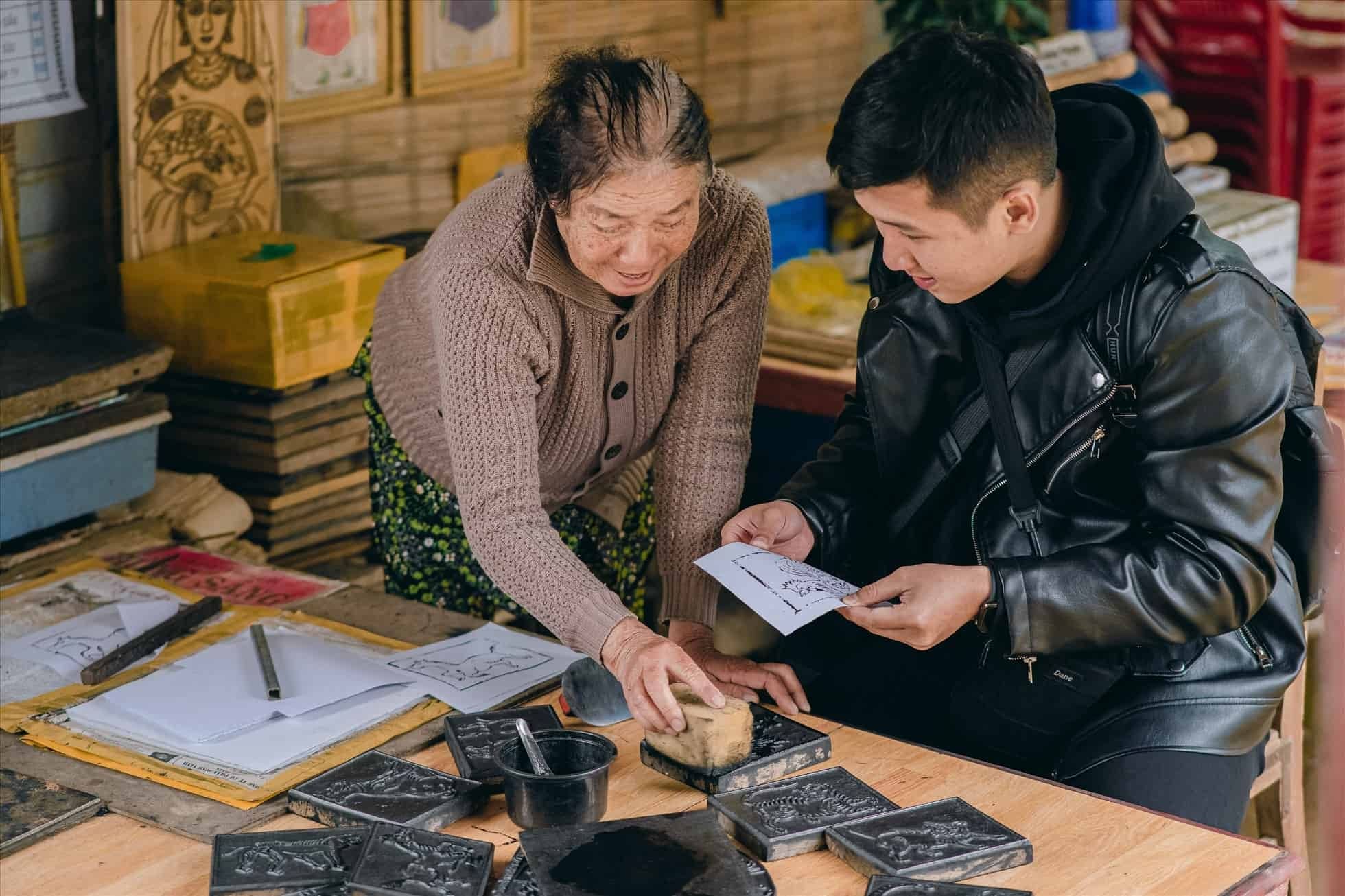 Nghệ nhân hướng dẫn in tranh cho khách tham quan