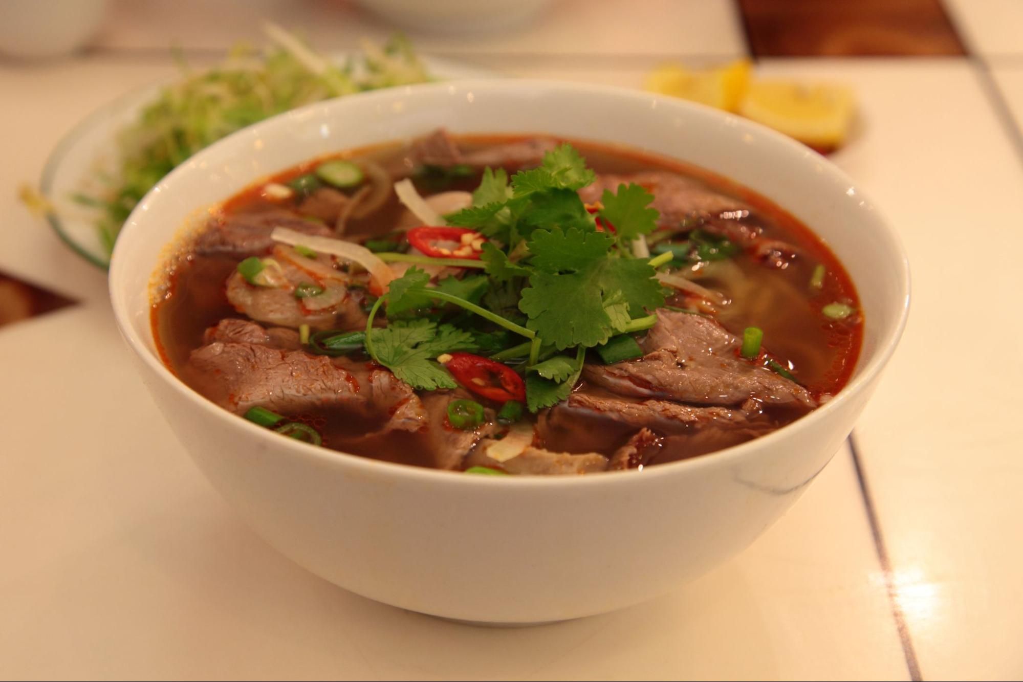 Một tô bún bò Huế nóng hổi với đầy đủ topping