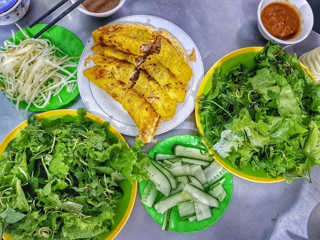Bánh xèo vàng giòn, cuốn rau sống và nước chấm cay ngọt.