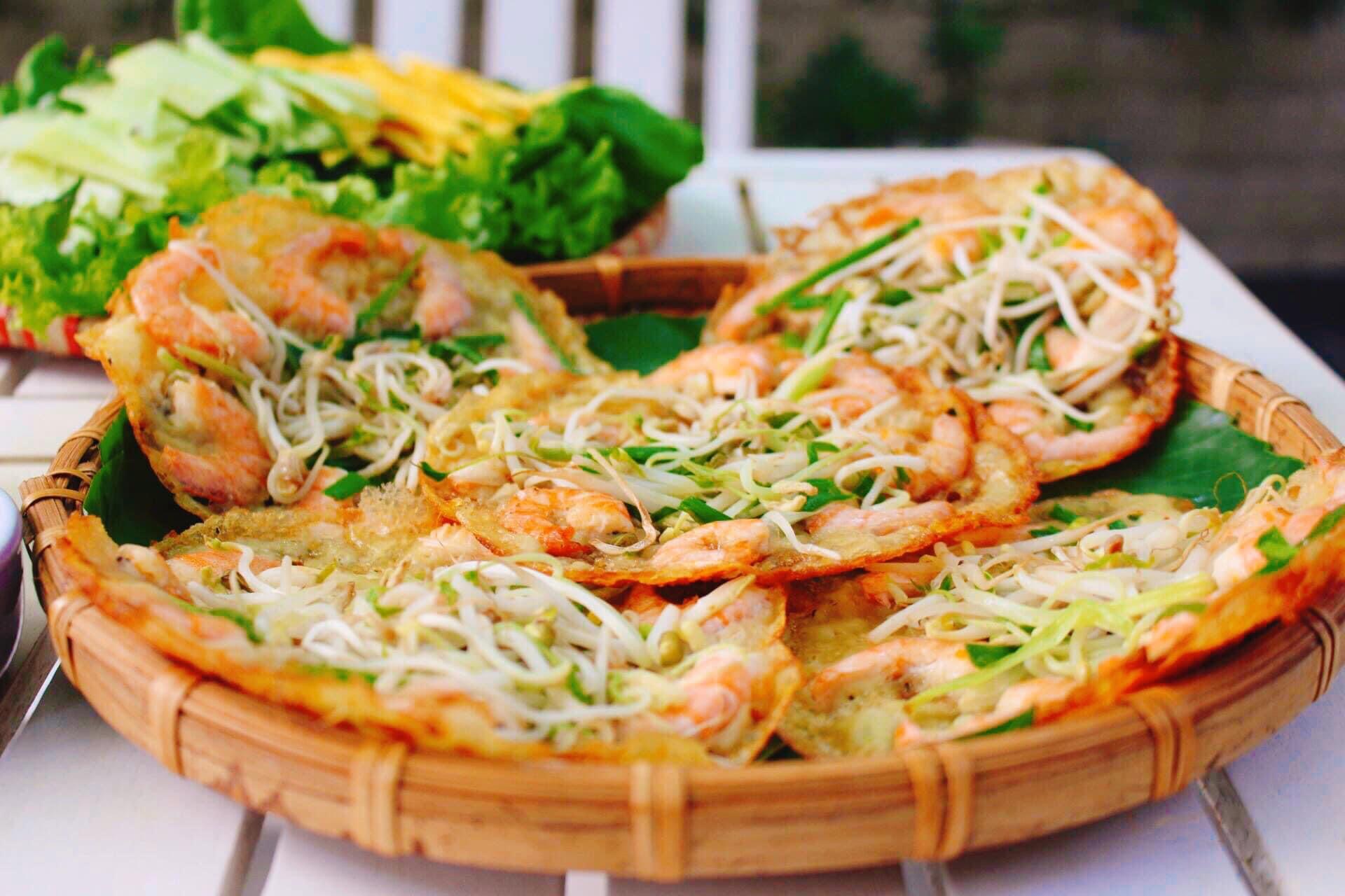 Một đĩa bánh xèo tôm nhảy vàng giòn, ăn kèm rau sống