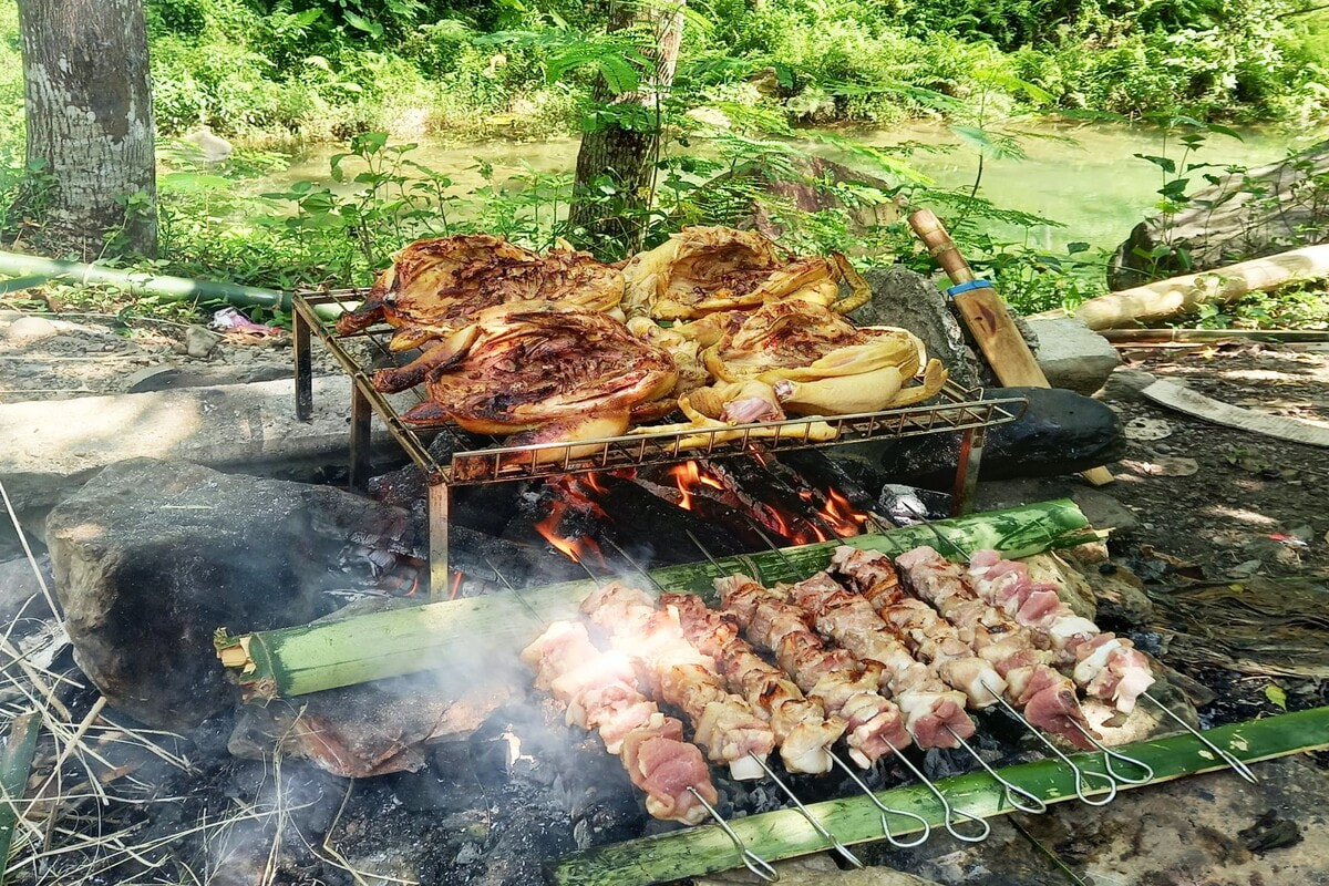 Một nhóm bạn đang mở tiệc nướng thịt bên bờ suối