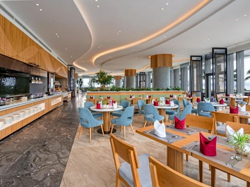 Không gian nhà hàng với bàn ghế hiện đại, ánh sáng tự nhiên và view hướng biển.