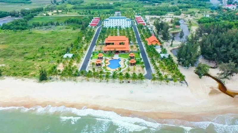 Không gian nghỉ dưỡng xanh mát với hồ bơi rộng lớn tại một resort sát biển Cam Bình